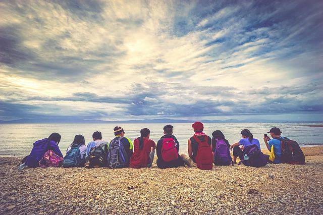 Eine Gruppe junger Menschen sitzen im Kreis am Strand