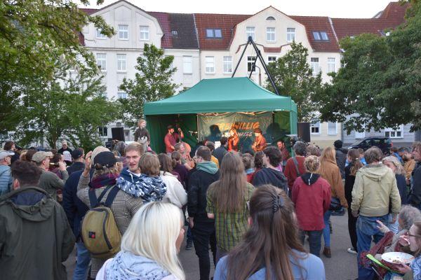viele Menschen vor einer Bühne, wo eine Band spielt
