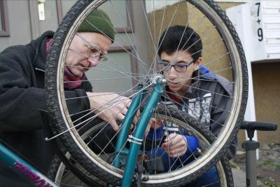 Ein Erwachsener und ein Jugendlicher bauen am Fahrrad