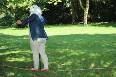 Eine Frau mit KOpftuch ballanciert auf einer Slackline