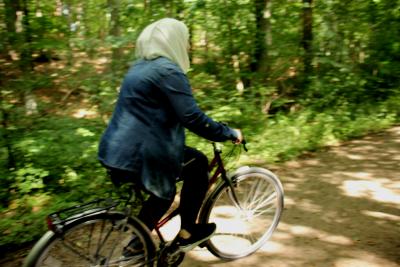 Eine Frau mit einem Kopftuch fährt Fahrrad